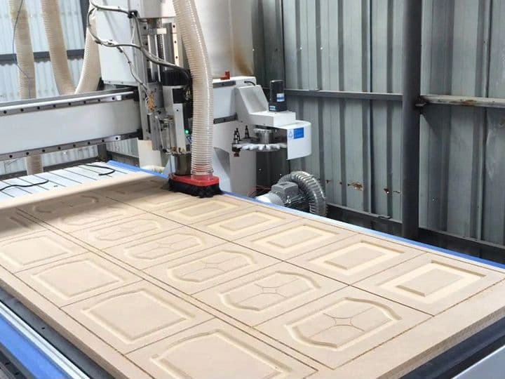 CNC router cutting a sheet of raised-panel cabinet doors